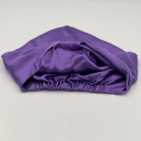 A purple silk bonnet laying flat but inside out so the double layering of silk can be seen