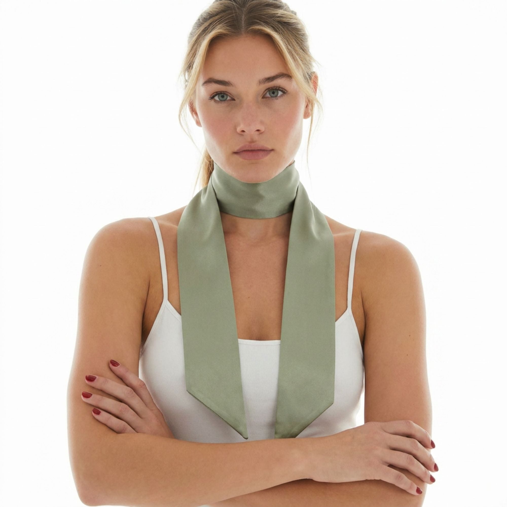 Woman wearing a sage green silk skinny scarf around her neck on a white background