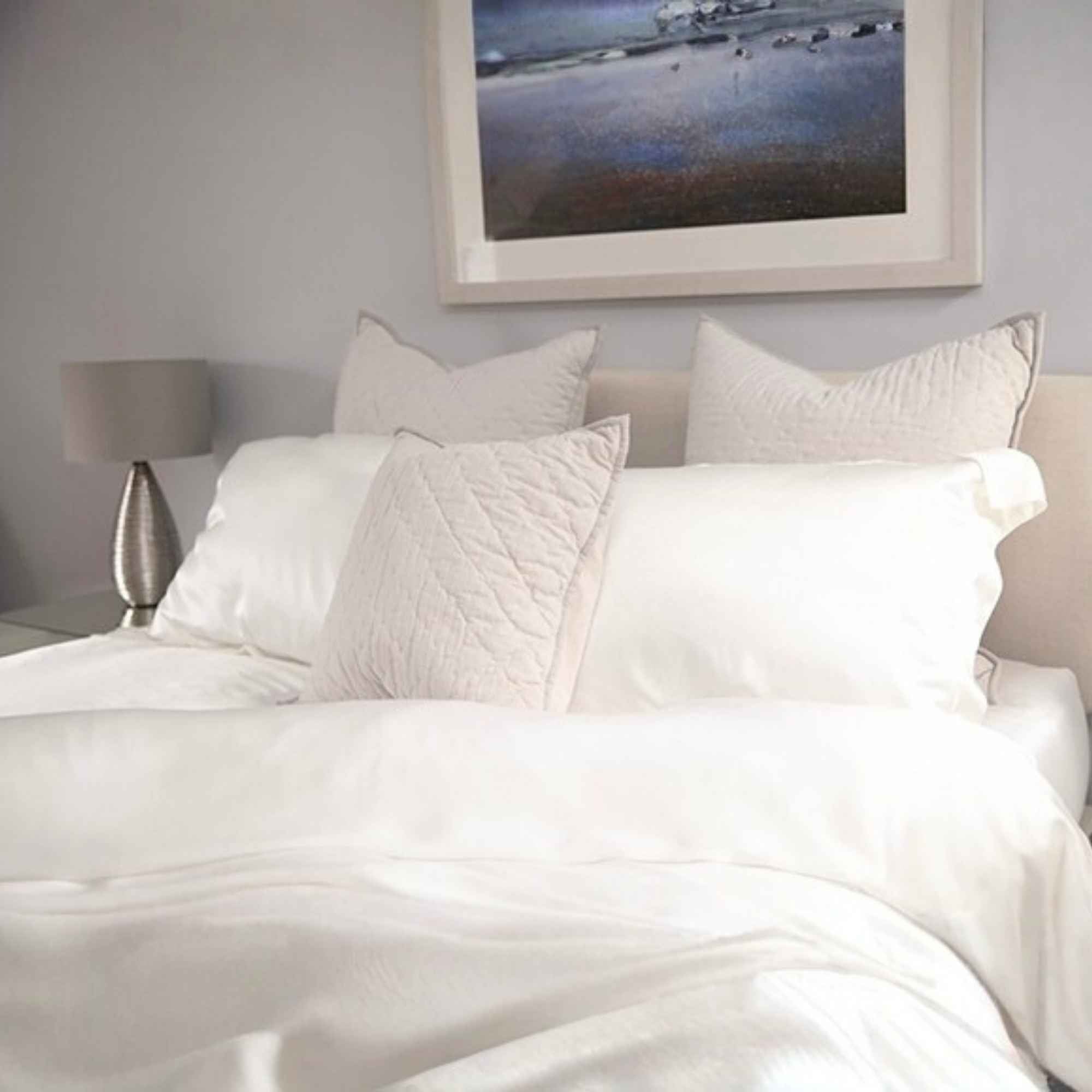 silk bed set in a grey room. the silk duvet cover in folded back at the corner and the picture is taken near the foot of the bed