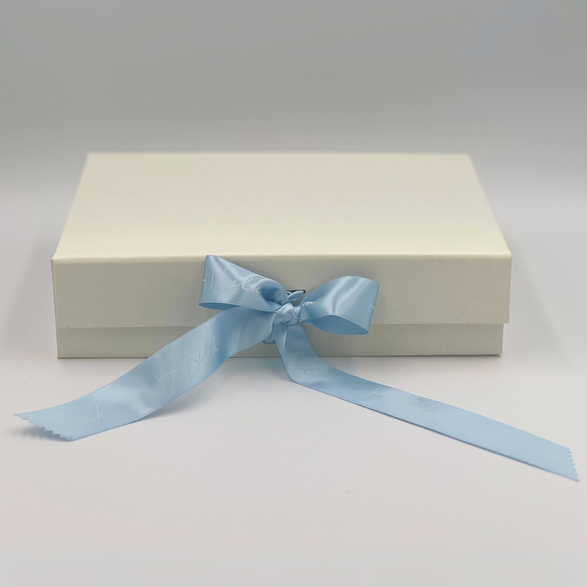 buttermilk gift box with a baby blue hi silk ribbon tied in a bow on the front