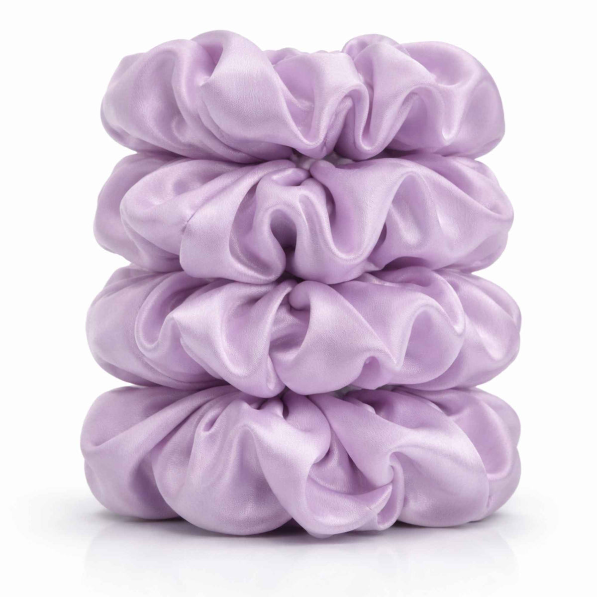 Stack of four lavender purple silk scrunchies on a white background
