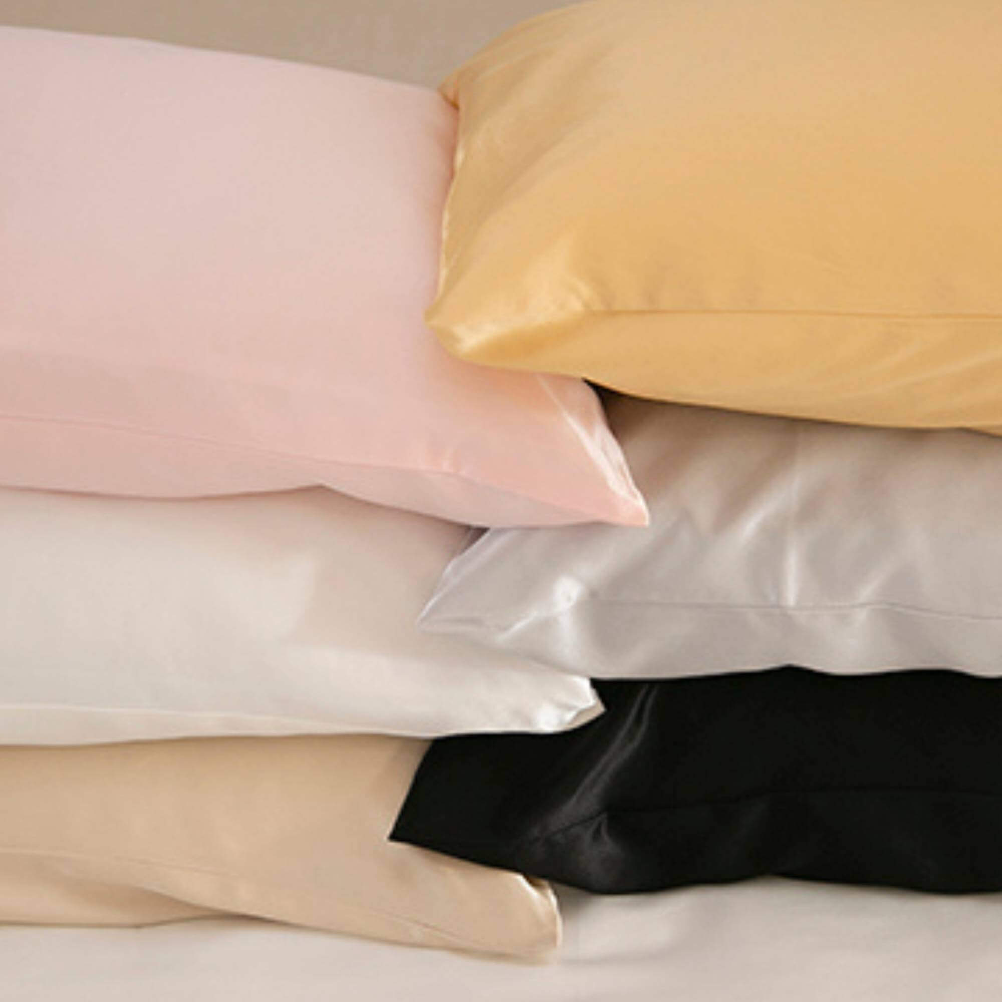 Stack of silk pillows in various colors on a neutral background