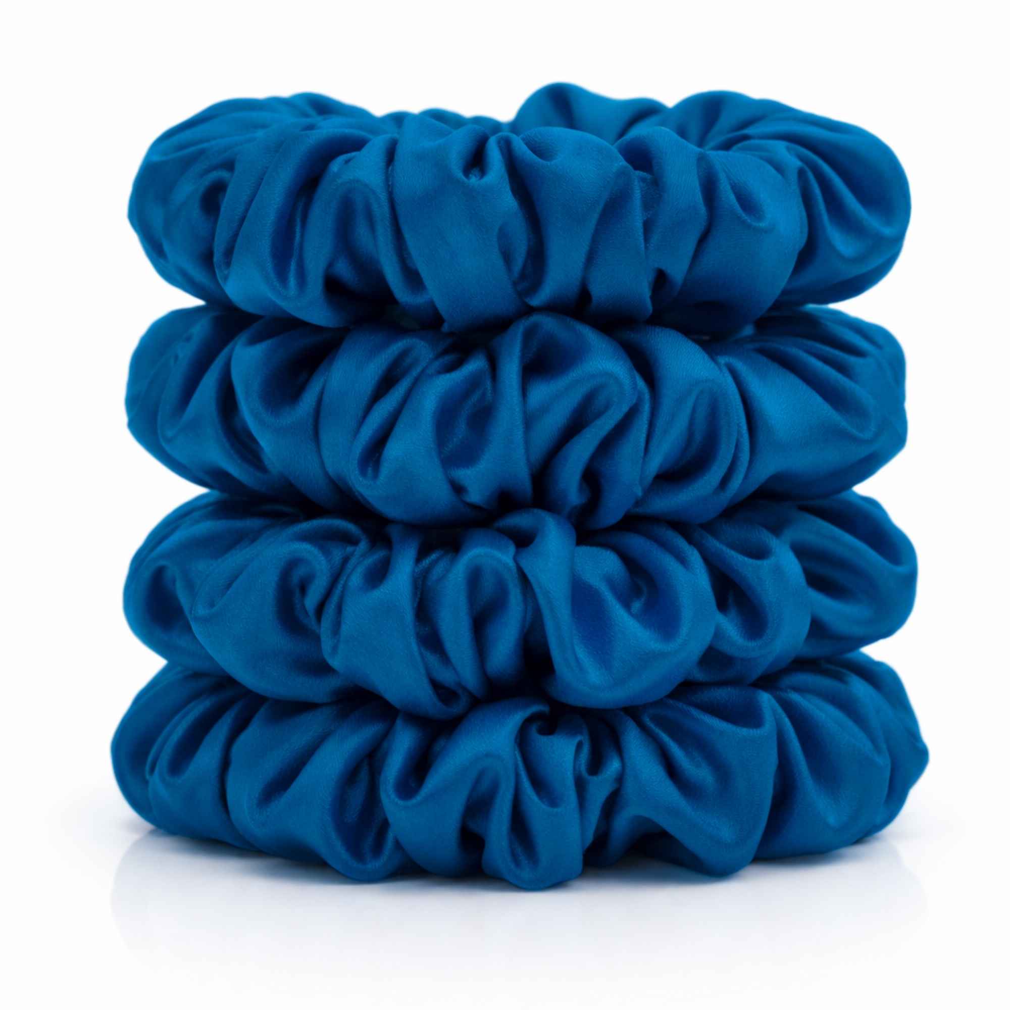 Stack of crystal teal silk scrunchies on a white background