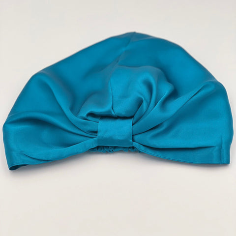 Front view on a teal silk bonnet laying flat