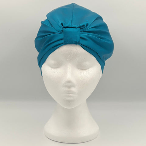 Front view of a teal silk bonnet on a mannequin