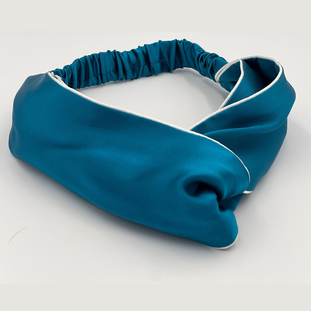 A teal silk headband lying flat