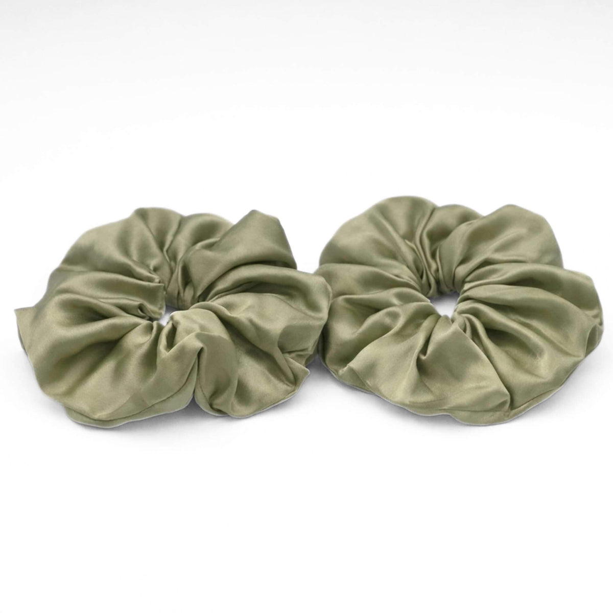 Two pistachio green jumbo silk scrunchies on a white background