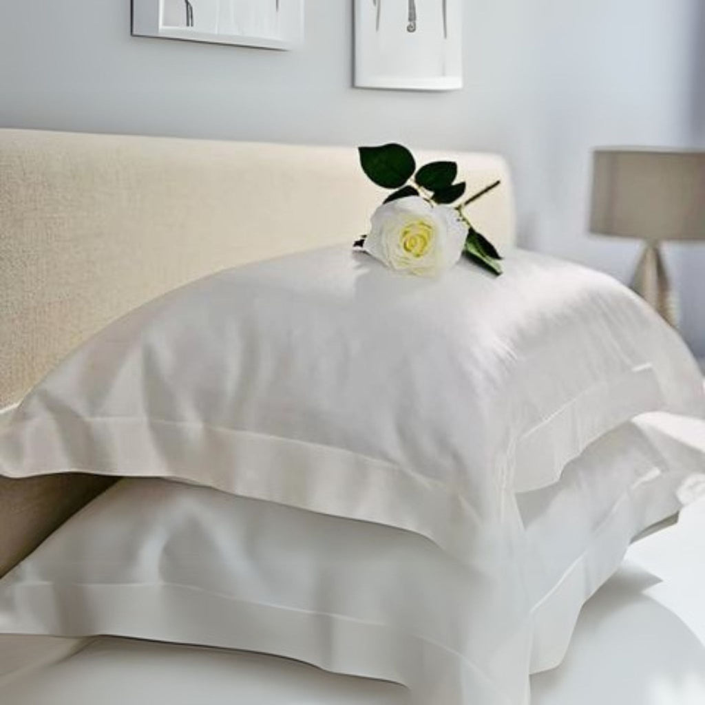 two ivory oxford 25 momme silk pillowcase stacked with a rose on top