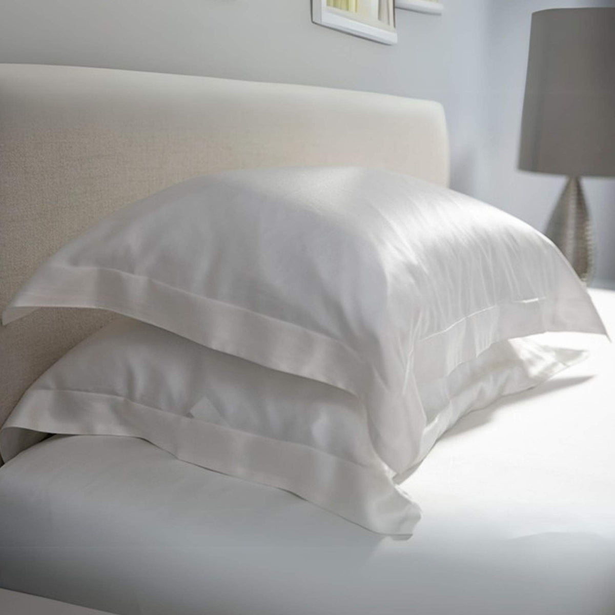 White silk pillows on a bed in a bedroom setting
