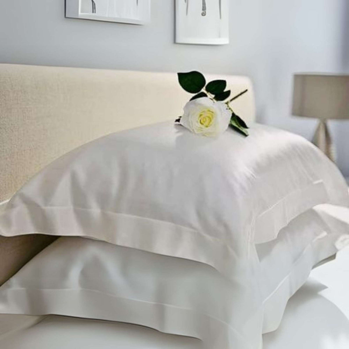two ivory silk oxford pillowcases on a bed with a rose on top