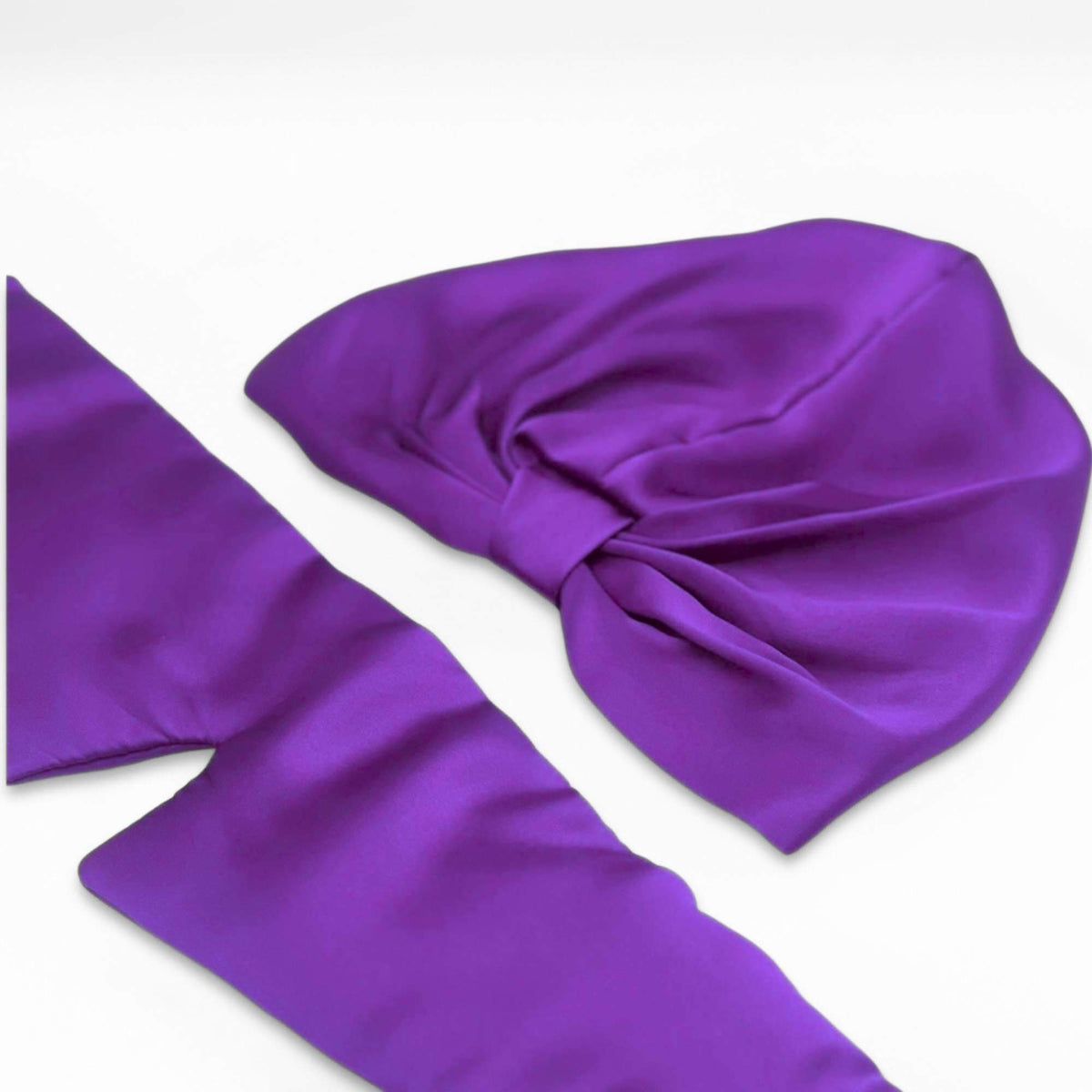 Purple silk bonnet and eye mask set on a light gray background