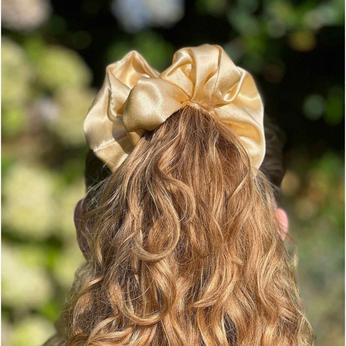 an oversized golden yellow mulberry silk scrunchie in a high ponytail