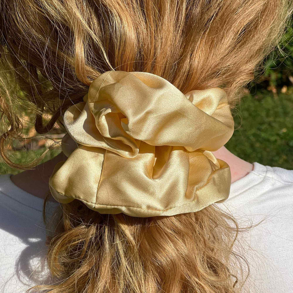 golden Yellow mulberry silk scrunchie on a person's hair with a blurred natural background